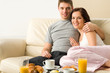 Photo: Cheerful couple sitting on couch before breakfast Cheerful couple sitting on couch before breakfast
