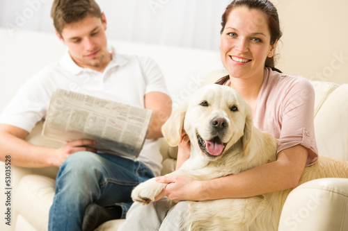 Photo: Resting joyful couple sitting and petting dog Resting joyful couple sitting and petting dog