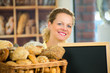 Foto: freundliche bäckereiverkäuferin mit hinweisschild freundliche bäckereiverkäuferin mit hinweisschild