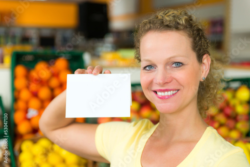 Photo: frau mit hinweisschild im obstladen frau mit hinweisschild im obstladen