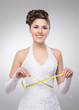 A young and beautiful bride measures her waist