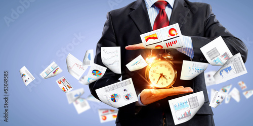 Photo: Business man holding alarmclock Business man holding alarmclock