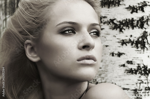 Photo: Beautiful blond woman near a tree in a forest Beautiful blond woman near a tree in a forest