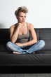 Fashion teenager girl pensive sitting on a couch