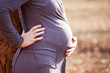 Young pregnant Caucasian woman holding her back and belly