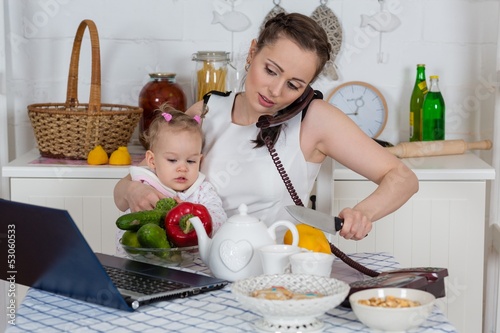 Photo: Mother with baby in kitchen. Mother with baby in kitchen.