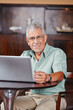 Lächelnder Senior am Laptop im Café