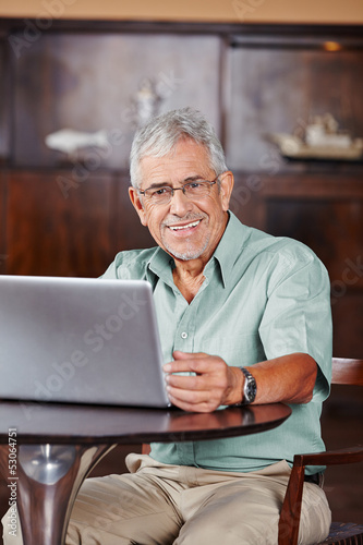 Photo: Lächelnder Senior am Laptop im Café Lächelnder Senior am Laptop im Café