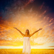 woman walking on wheat field over sunset