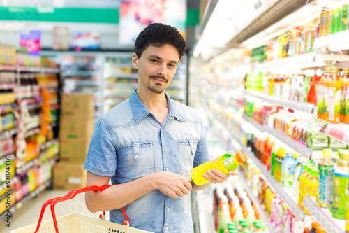 Photo: man in a supermarket buying a bottle of juice man in a supermarket buying a bottle of juice