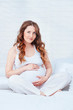 Pregnant woman sit on bed