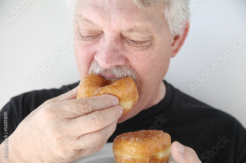 Photo: man biting into fresh doughnut man biting into fresh doughnut