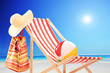 Beach chair with ball, bag and hat by the sea