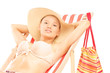 Beautiful smiling female in bikini enjoying on a beach chair