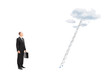 Businessman standing in front of a ladder with clouds looking up