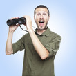 young man looking through binoculars, surprise face expression