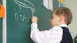 schoolboy writing on blackboard in classroom