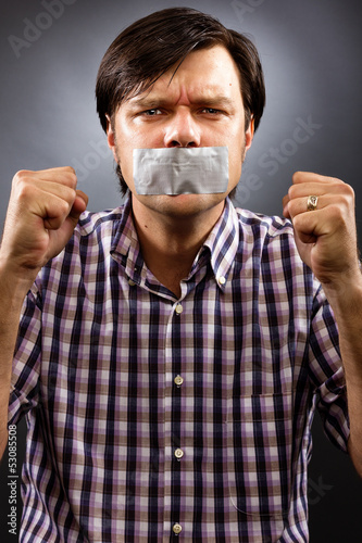 Photo: Angry young man with duct tape over his mouth Angry young man with duct tape over his mouth