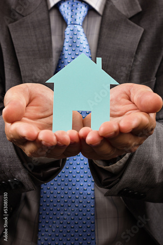 Photo: Business man holding a model of a house in his hands Business man holding a model of a house in his hands