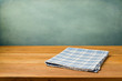 Wooden table with tablecloth over grunge blue wall