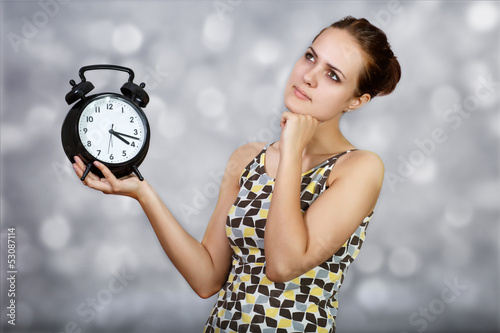 Photo: Thoughtful girl with alarm clocks at light background Thoughtful girl with alarm clocks at light background