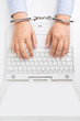 Foto: Female hands in handcuffs, with laptop, high angle view Female hands in handcuffs, with laptop, high angle view