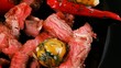 roast meat on black dish wuth red hot pepper and olives