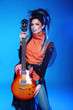 Rock girl posing with electric guitar isolated on blue backgroun