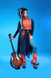 Rock girl posing with electric guitar isolated on blue backgroun