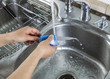 Female hands washing single small knife in kitchen sink