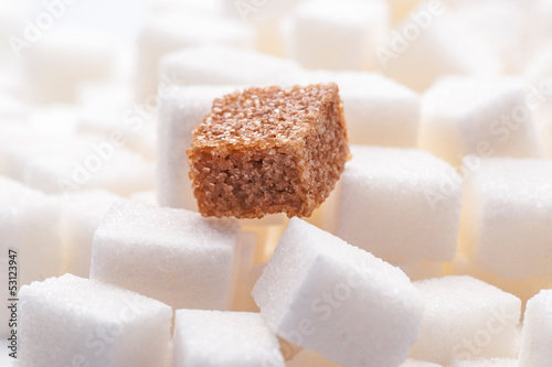 Photo: one brown sugar lump in front of lots of white sugar cubes backl one brown sugar lump in front of lots of white sugar cubes backl