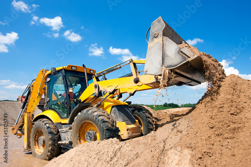 Photo: Excavator machine unloading sand during earth moving works Excavator machine unloading sand during earth moving works