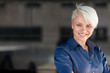 Businesswoman wearing shirt and smiling in front of a dark backg