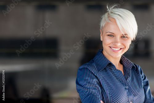 Photo: Businesswoman wearing shirt and smiling in front of a dark backg Businesswoman wearing shirt and smiling in front of a dark backg