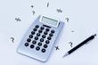 calculator with different symbols around and a pen on the side