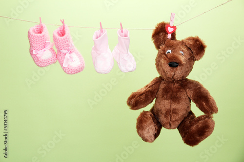 Photo: Baby booties hanging on clothesline, on color background Baby booties hanging on clothesline, on color background