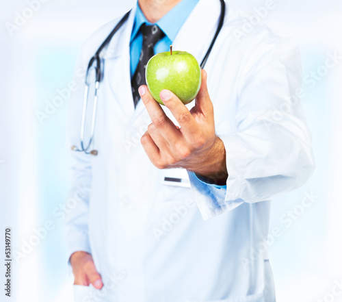 Photo: Doctor's hand holding a fresh green apple close-up Doctor's hand holding a fresh green apple close-up