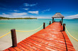 Wooden red jetty extending to tropical lagoon