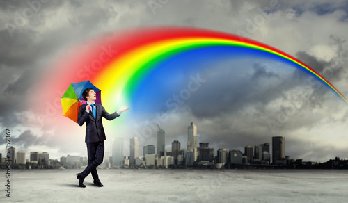 Photo: Businessman with umbrella atop of building Businessman with umbrella atop of building