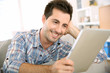 Photo: Cheerful handsome guy using tablet to read mail Cheerful handsome guy using tablet to read mail