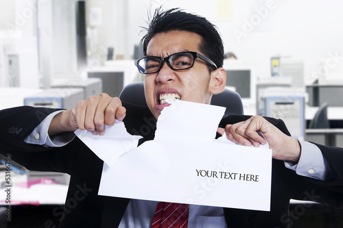 Photo: Angry businessman tear paper at office Angry businessman tear paper at office