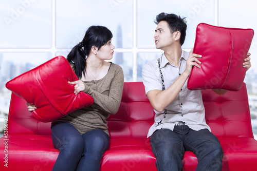 Photo: Angry couple on red sofa at apartment Angry couple on red sofa at apartment
