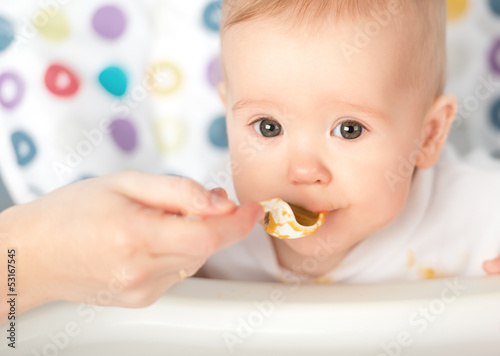 Photo: Mother feeds funny baby from spoon Mother feeds funny baby from spoon
