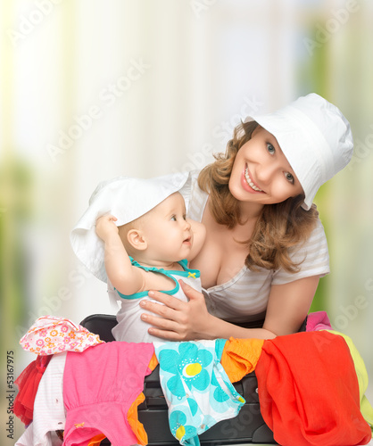 Photo: Mom and baby girl with suitcase and clothes ready for traveling Mom and baby girl with suitcase and clothes ready for traveling