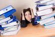 Frustrated businesswoman with stack of folders at office
