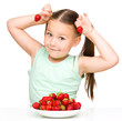 Photo: Happy little girl is eating strawberries Happy little girl is eating strawberries