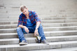 Drunk man sitting on the stairs drinking wine and smoking cigare