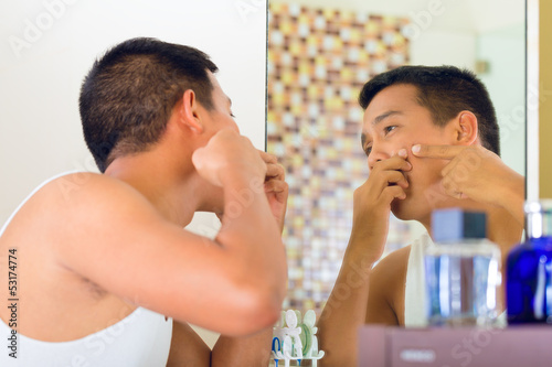 Photo: Asian man discovering a pimple in face Asian man discovering a pimple in face