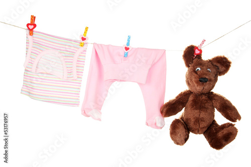 Photo: Baby clothes hanging on clothesline, isolated on white Baby clothes hanging on clothesline, isolated on white