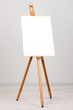 Wooden easel with clean paper in room